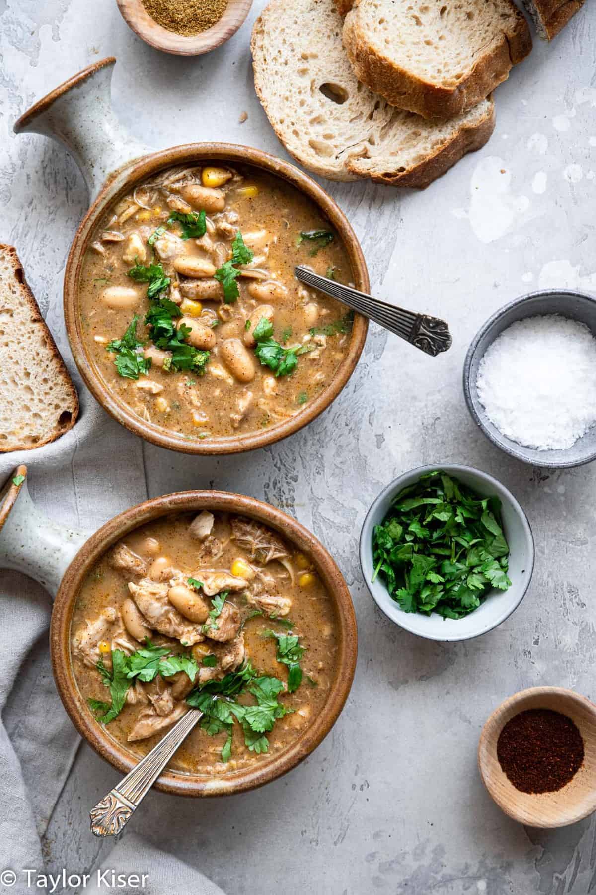 two bowls of Crockpot White Chicken Chili with cilantro and salt