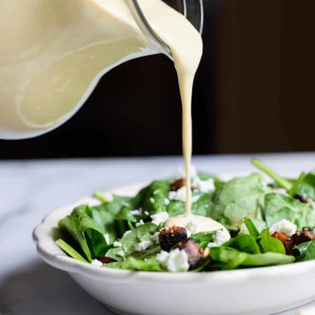 pouring tahini salad dressing onto a salad