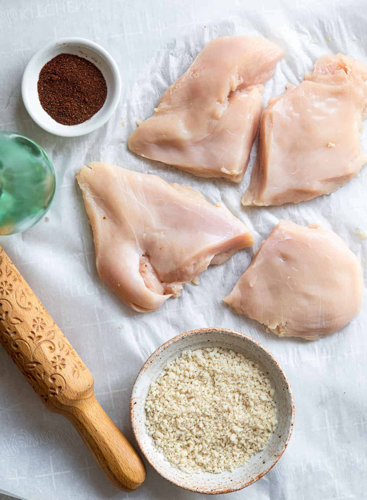 raw chicken being flattened for Air Fryer Breaded Chicken Breast